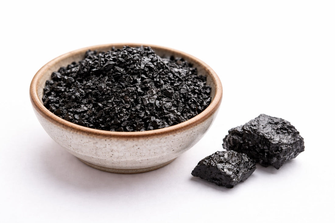 Shilajit pur en morceaux et poudre noire dans un bol en céramique sur fond blanc